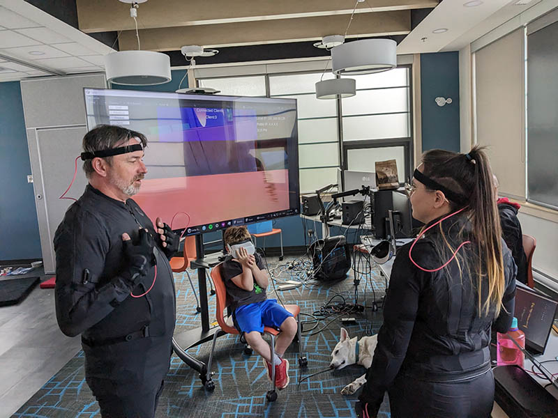 Caption: Wearing a motion capture suit at the Centre for Research and Innovation, Mark Bradbury, artistic director, Hard Ticket Theatre, confers with Chelsea O'Hara of DCXIX, a software development company that has recently moved to the west coast of the island (and that's Christopher Bradbury hiding in the middle!).
